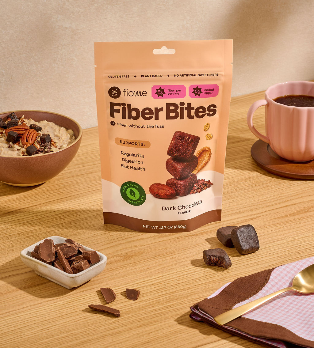Fiome Dark Chocolate Fiber Bites beside a cup of black coffee and a bowl of oatmeal
